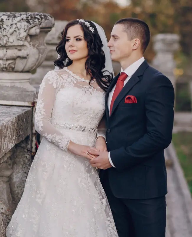 Couple in wedding attire standing together outdoors.