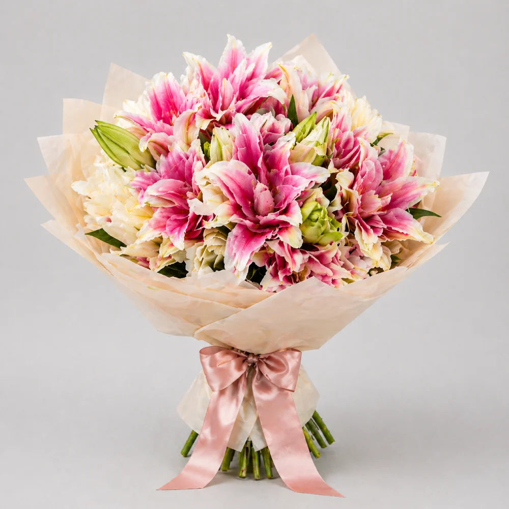Bouquet of pink and white flowers wrapped in brown paper with a pink ribbon on a light gray background
