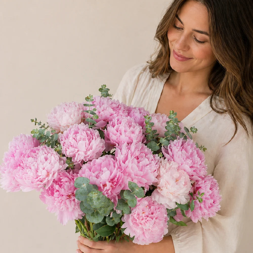 Woman holding a bouquet of pink flowers against a beige background