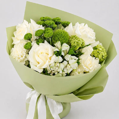 Bouquet of white and green flowers wrapped in green paper with a white ribbon on a light gray background